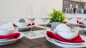 A dining table set with white plates, red napkins, and clear glasses, with a small potted plant in the center. - Stunning 2Bd Apto Close to Disney @ Storey Lake 105 3171 (Kissimmee)