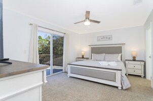 Ein Schlafzimmer mit Bett, Nachttischen, Deckenventilator und Blick ins Freie.
