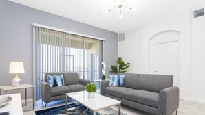 A modern living room with two grey sofas, a white coffee table, and a blue patterned rug.