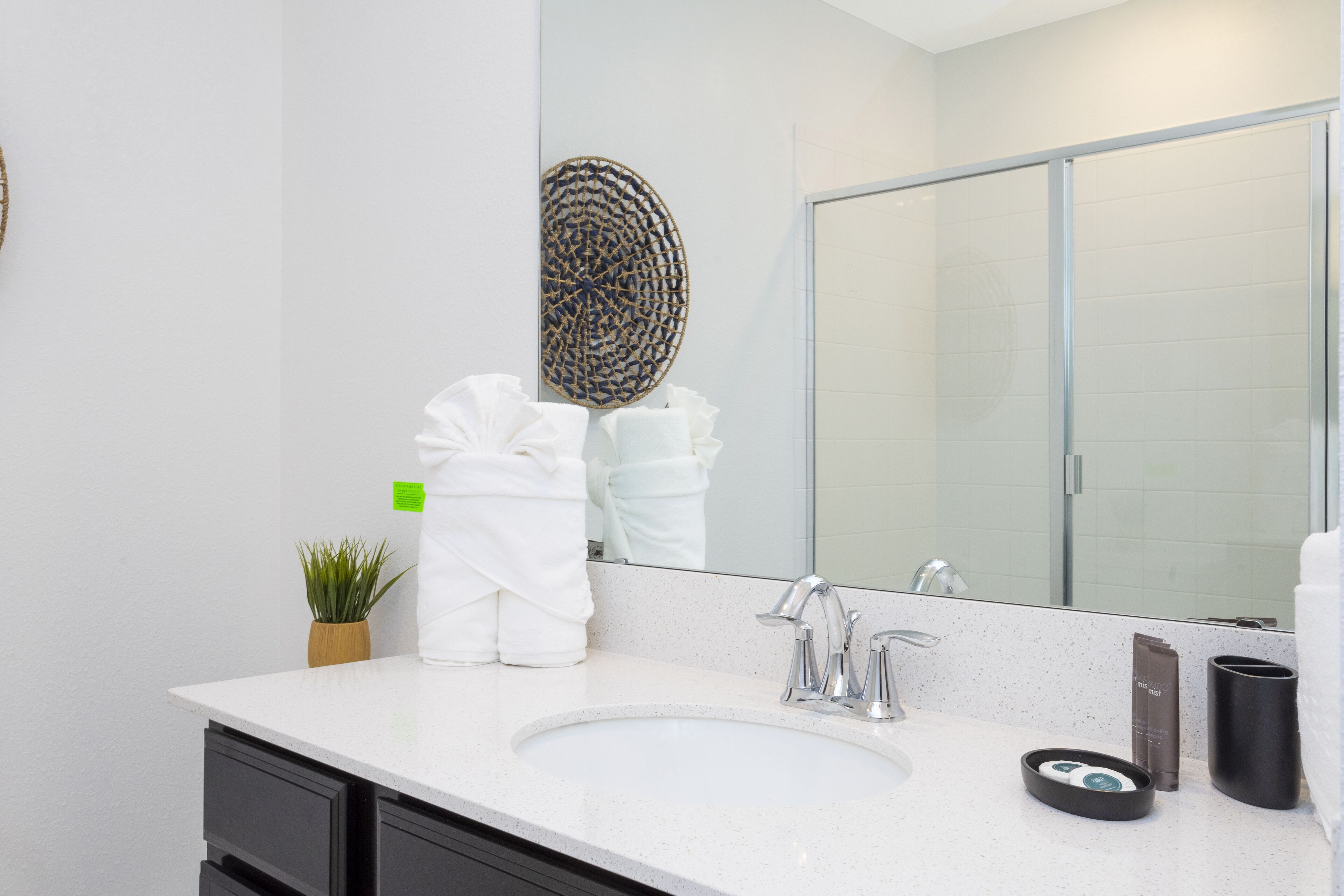 Une salle de bain moderne avec un lavabo blanc, un grand miroir et une cabine de douche.
