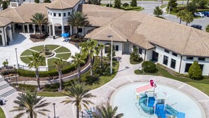 An aerial view of a hotel with a central courtyard, palm trees, and a swimming pool with a slide.