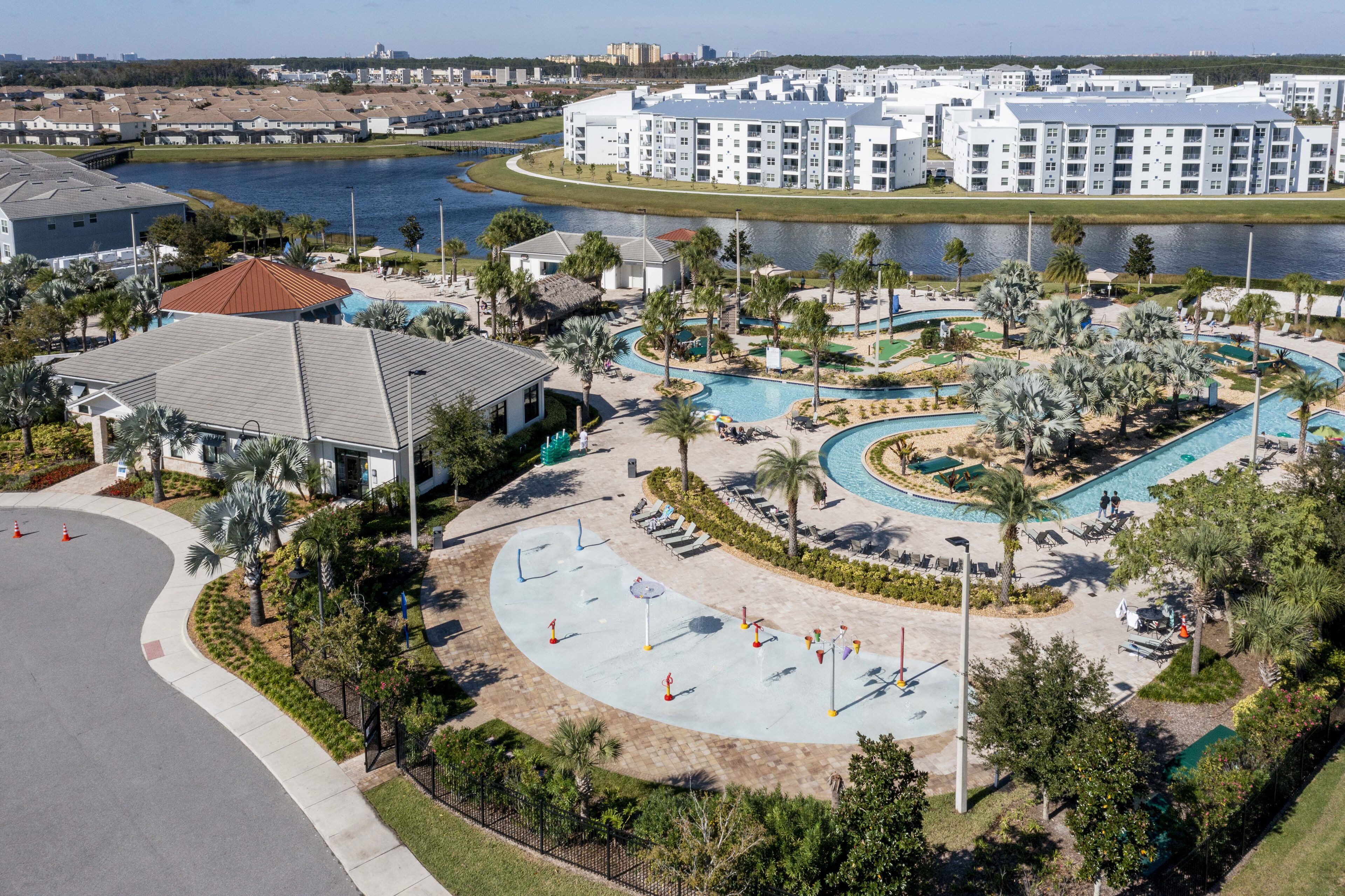 A resort with a large pool area, a tennis court, and a waterfront view.