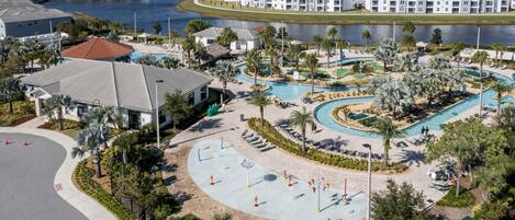 A resort with a large pool area, a tennis court, and a waterfront view.