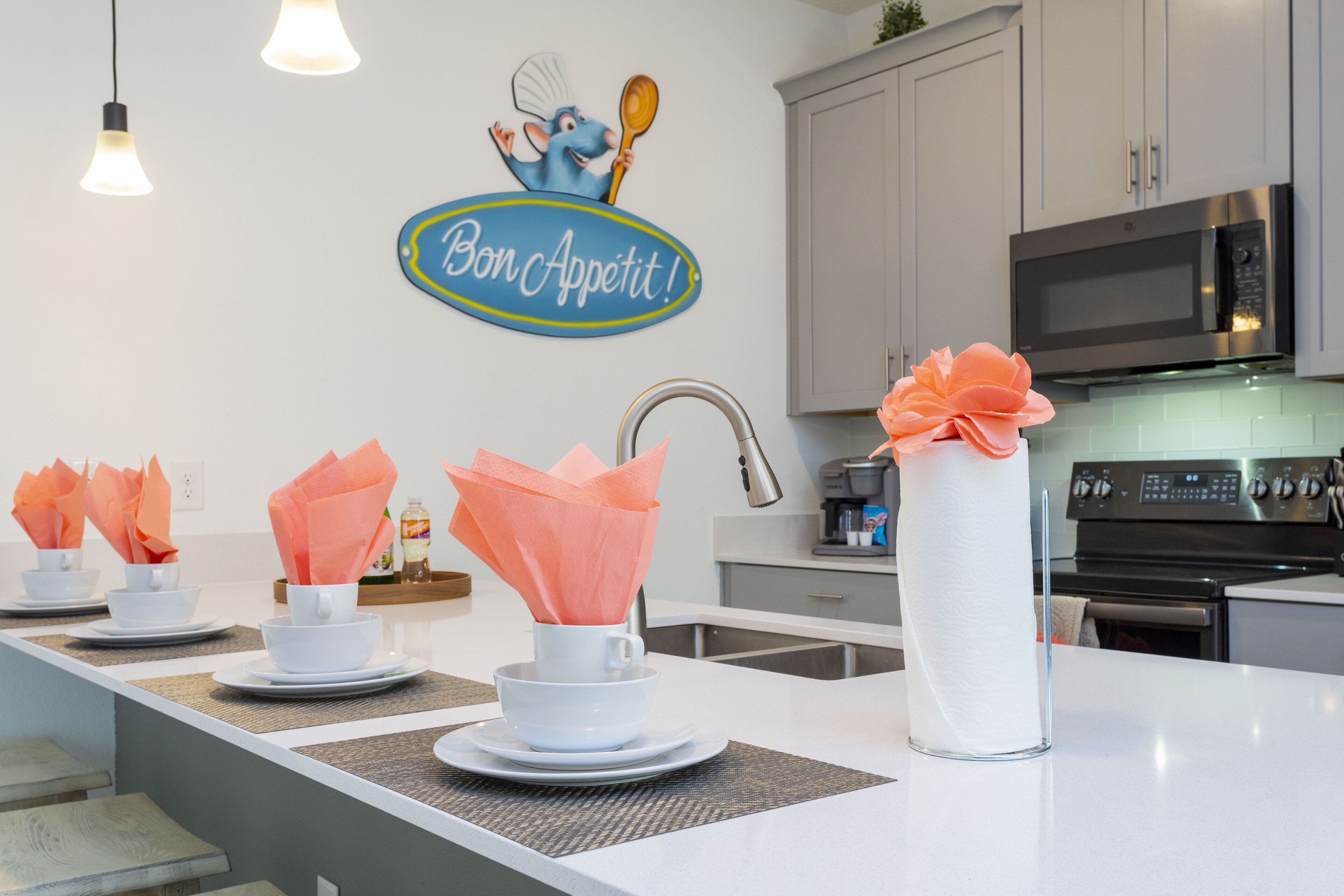 A modern kitchen with white cabinetry, a stainless steel microwave, and a decorative wall sign.