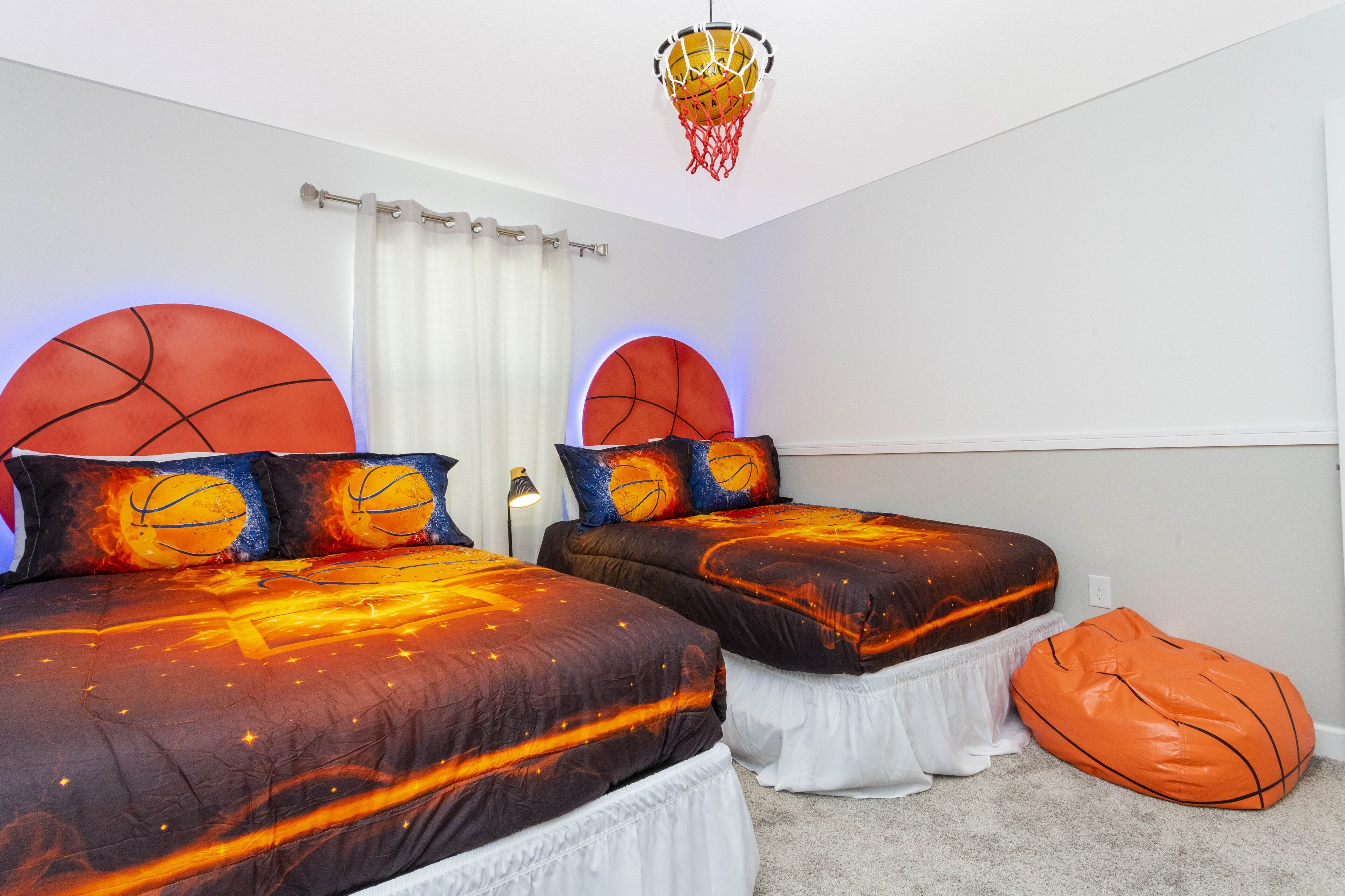 Un dormitorio con dos camas, cada una con una cabecera temática de baloncesto y ropa de cama a juego.