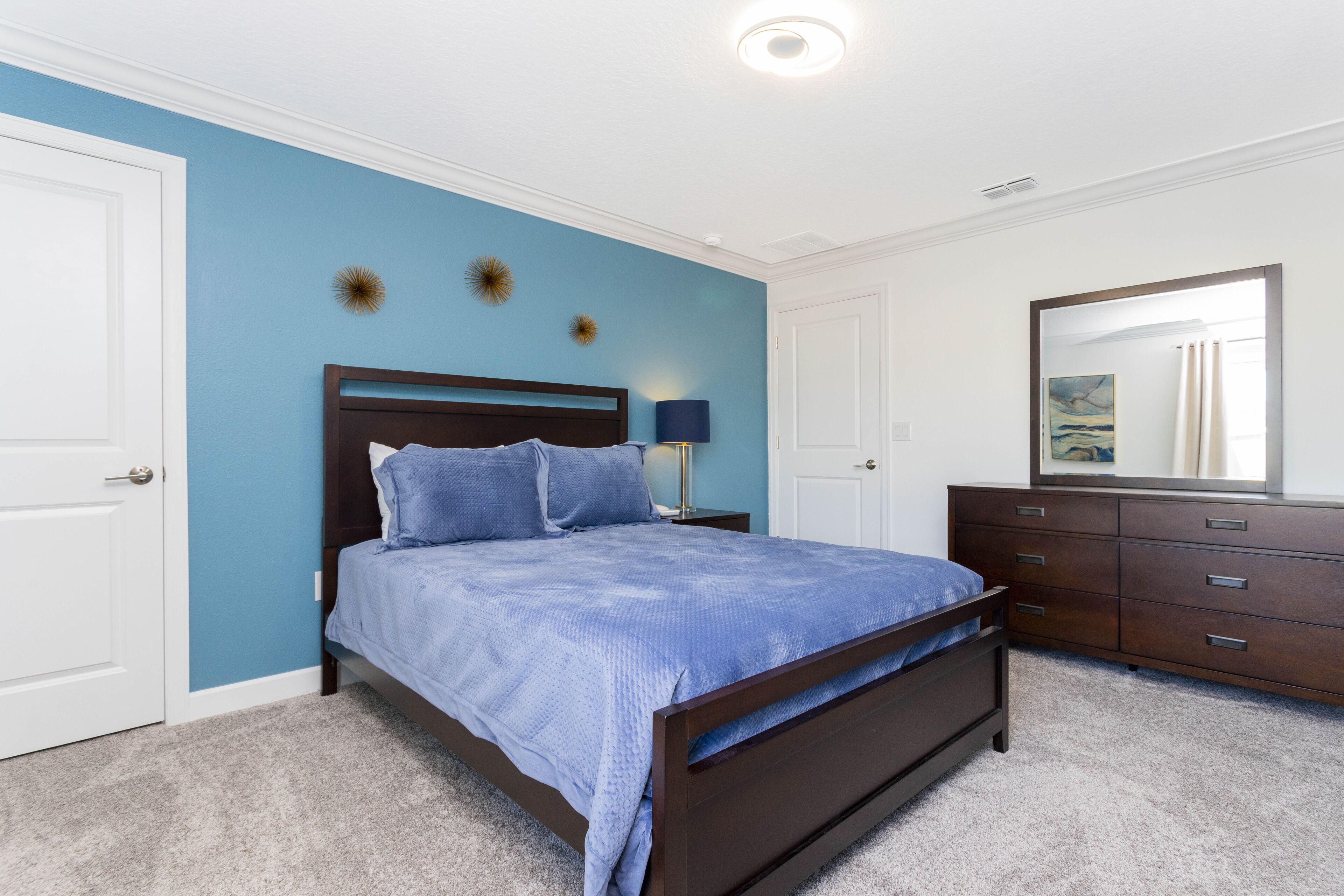 A bedroom with a bed, dresser, and a mirror.