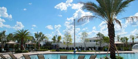 A pool area with lounge chairs and palm trees.