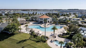 A resort with a central swimming pool, surrounded by palm trees and lounge areas.