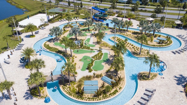 Vista aérea de un complejo turístico con una gran piscina, toboganes acuáticos y una zona de mini golf.