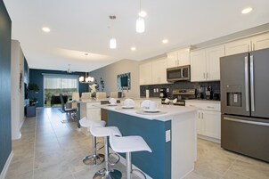 A modern kitchen with white cabinets, stainless steel appliances, and a central island with bar stools.
