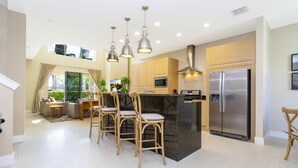 A modern kitchen with a central island, stainless steel appliances, and pendant lighting. - Marvelous 4 Bd Close to Disney @ Magic Village 3153 (Kissimmee)