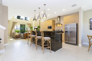 A modern kitchen with a central island, stainless steel appliances, and pendant lighting.