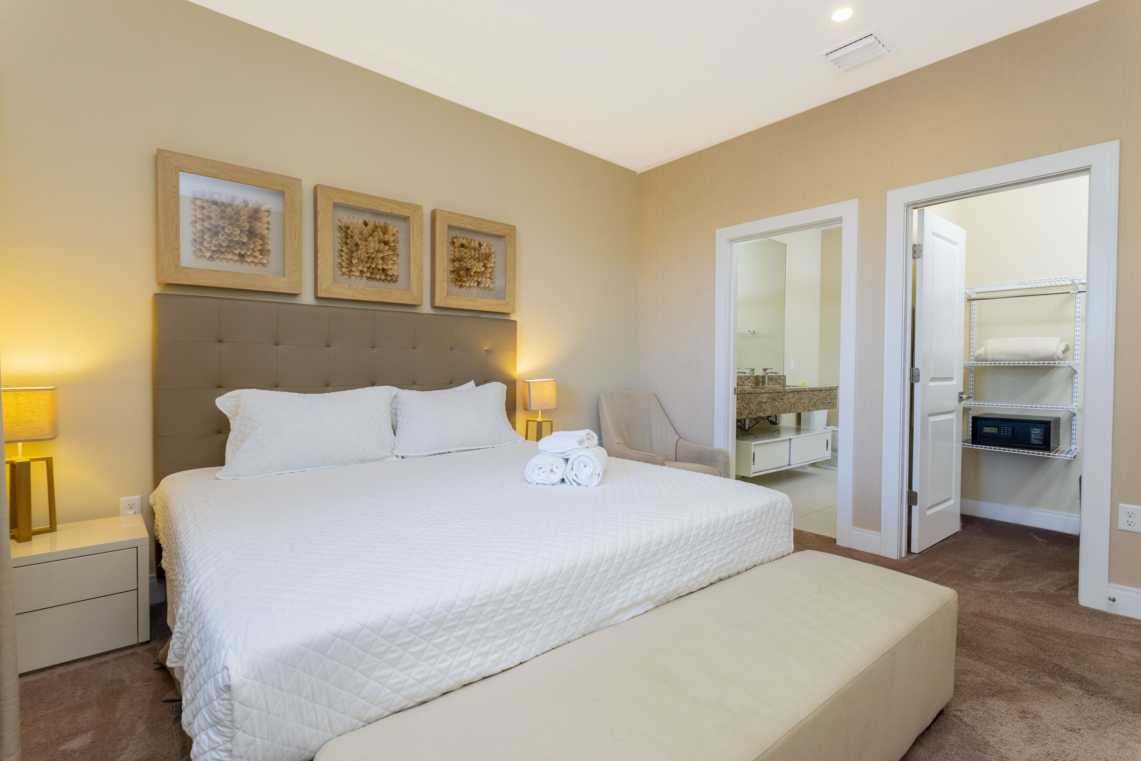 A hotel room with a large bed, bedside tables, a chair, and a walk-in closet.