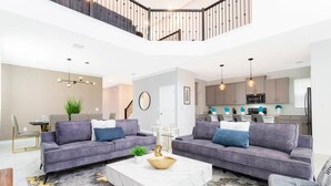 A modern living room with two grey sofas, a white coffee table, and a staircase leading to an upper level.