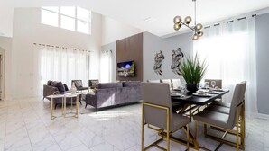 A spacious living area with a modern dining table, comfortable seating, and a large window providing natural light.