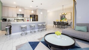 Een moderne keuken met roestvrijstalen apparatuur, een eethoek met een tafel en stoelen, en een woonkamer met een bank en salontafel.