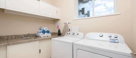 A laundry room with a washer and dryer, a window with a view, and a countertop with towels.