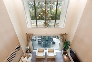Un salon spacieux avec de hauts plafonds et une grande fenêtre donnant sur un patio.
