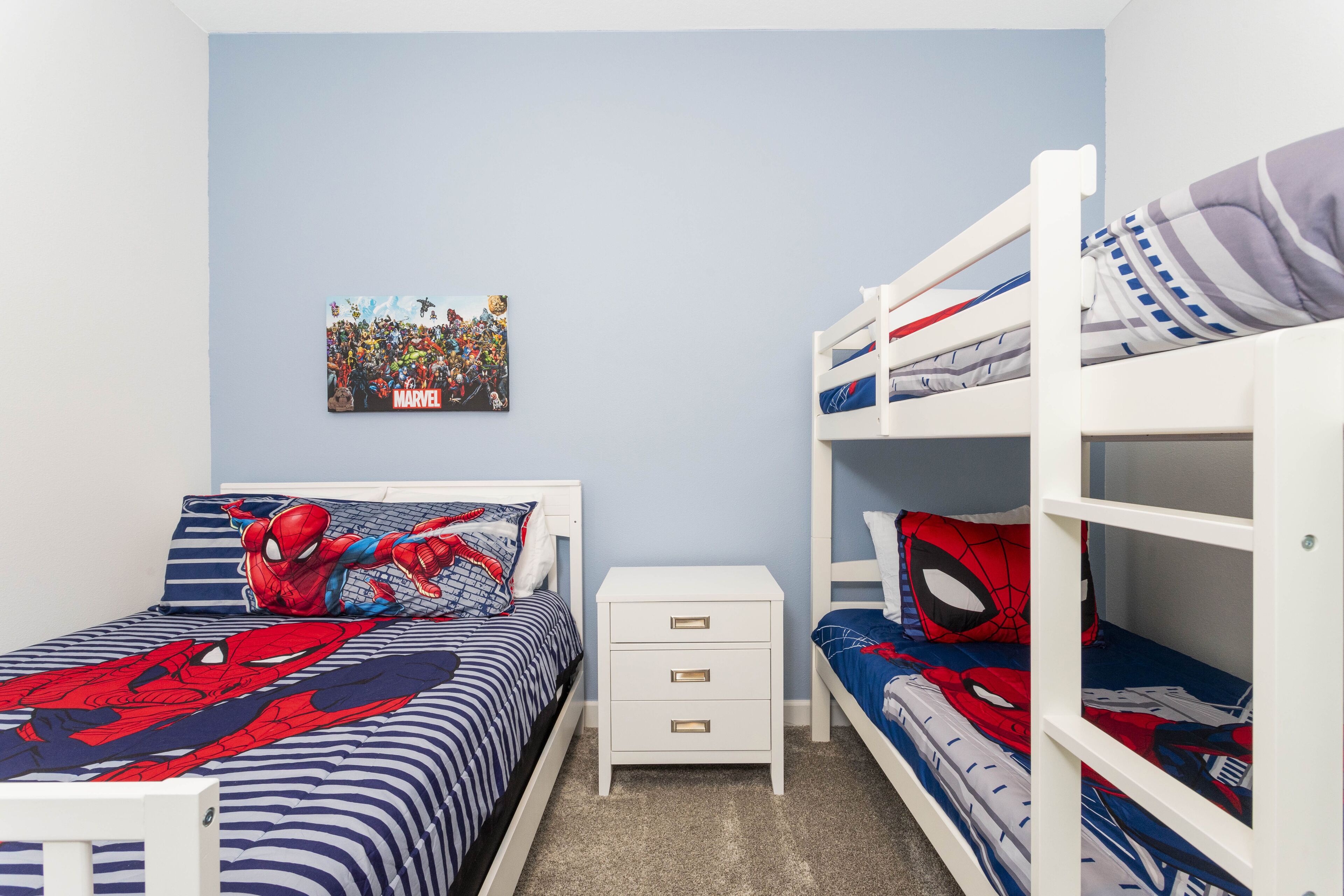 A bedroom with a bunk bed, a single bed, and a nightstand.