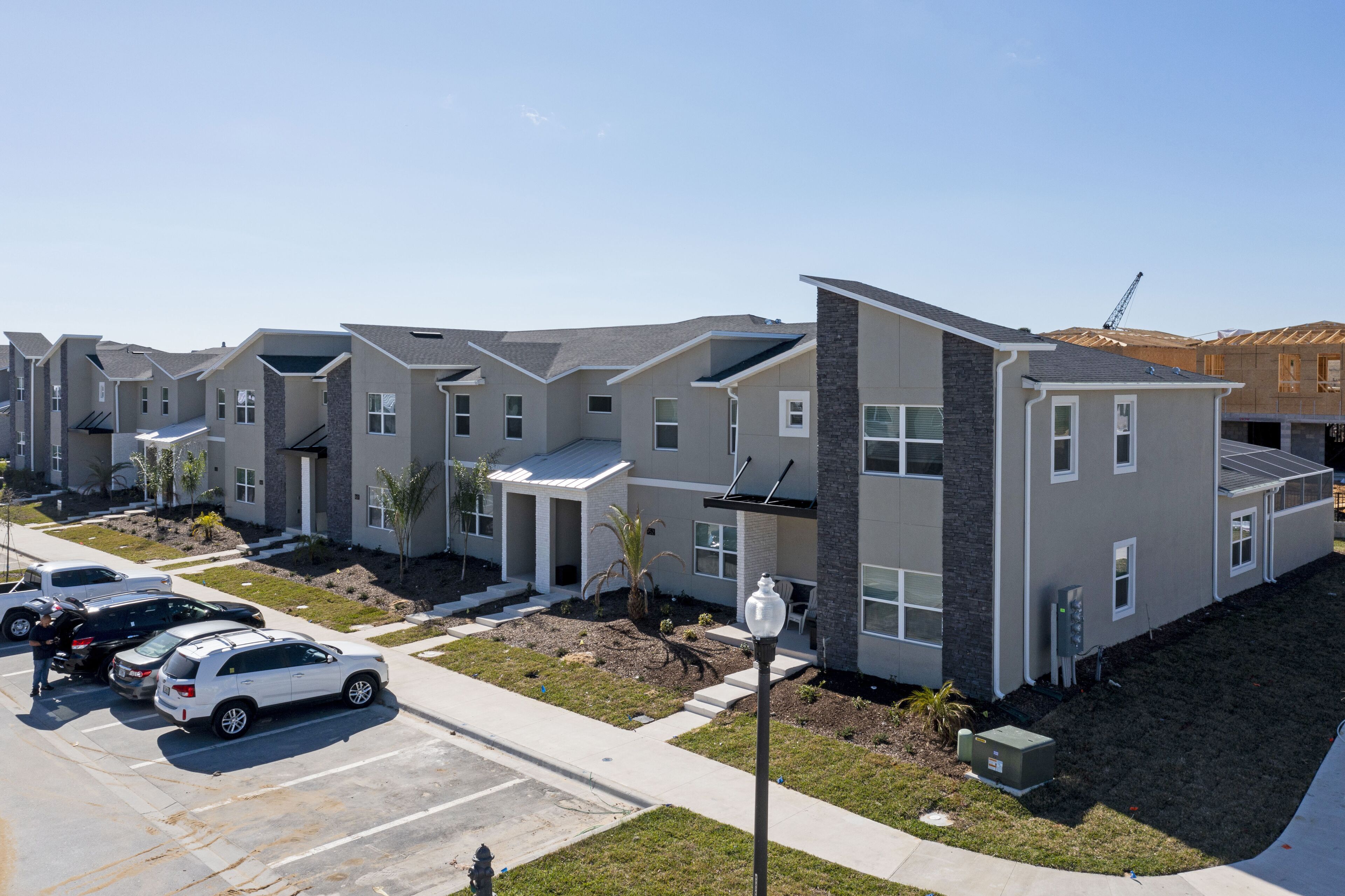 A row of modern townhouses with a parking lot in front.