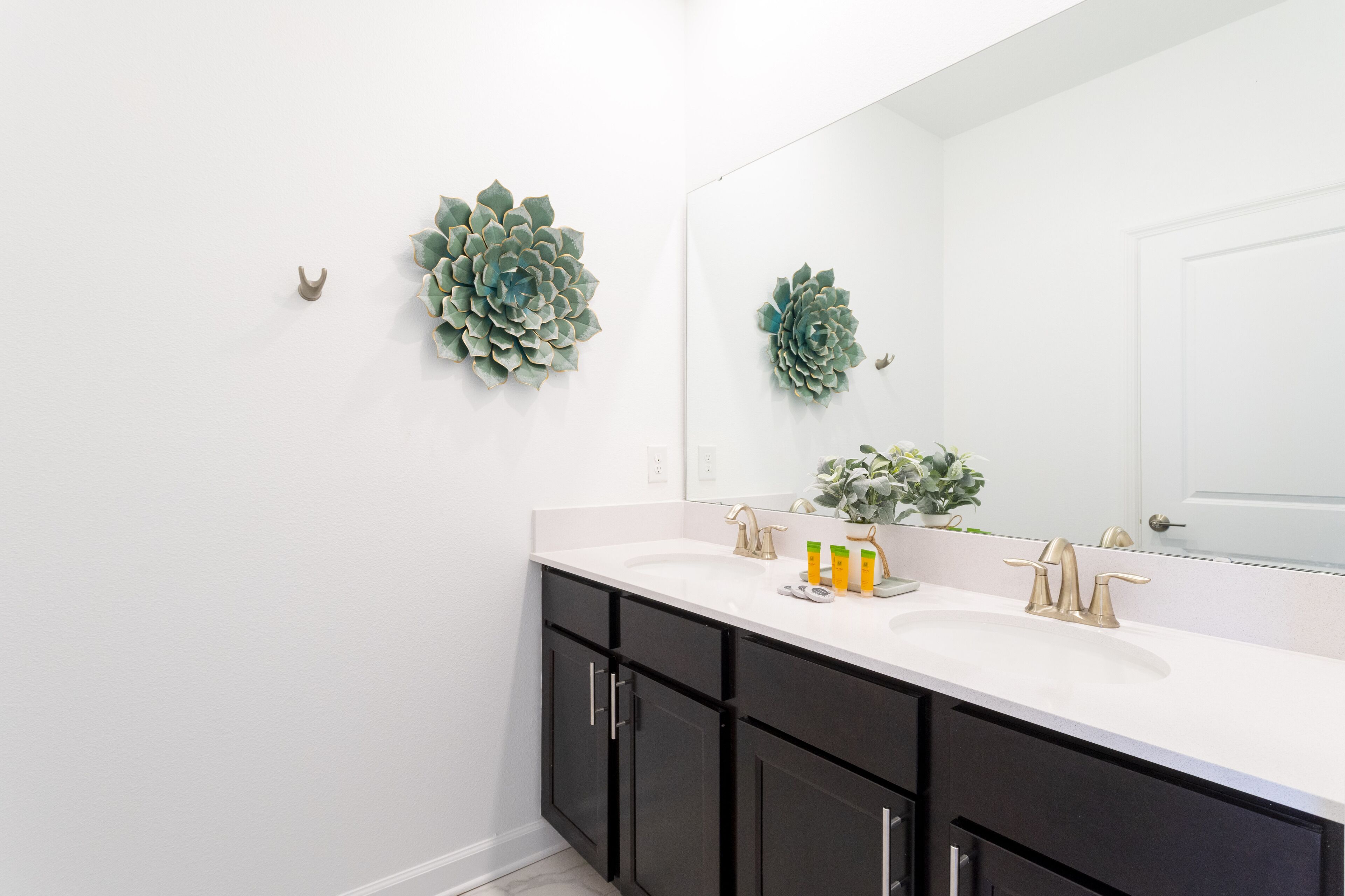 Un baño moderno con un lavamanos blanco, muebles oscuros y decoración mural.