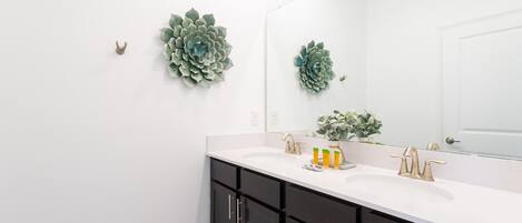 Un baño moderno con un lavamanos blanco, muebles oscuros y decoración mural.