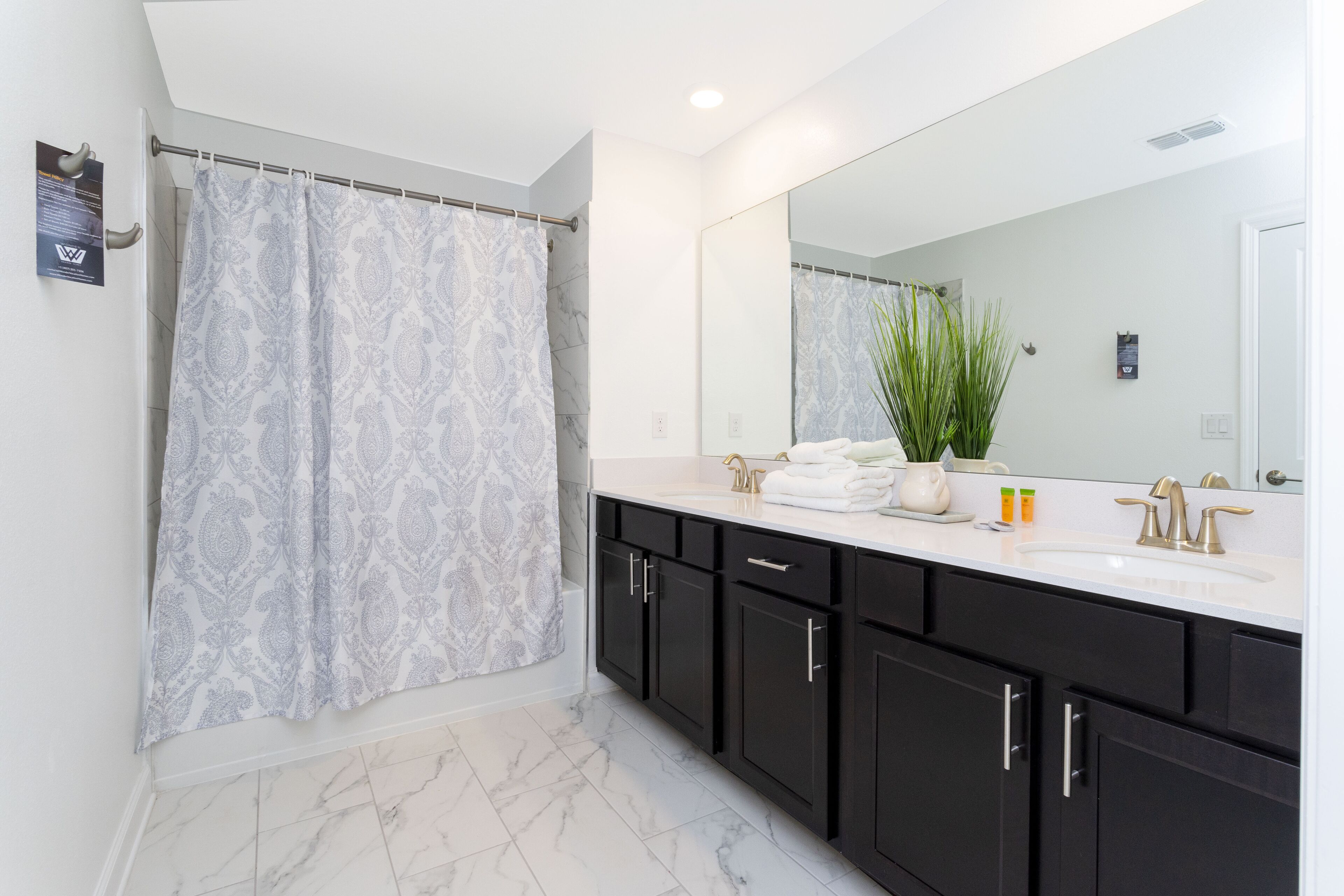 Une salle de bain moderne avec une douche, un grand miroir et un sol en marbre.