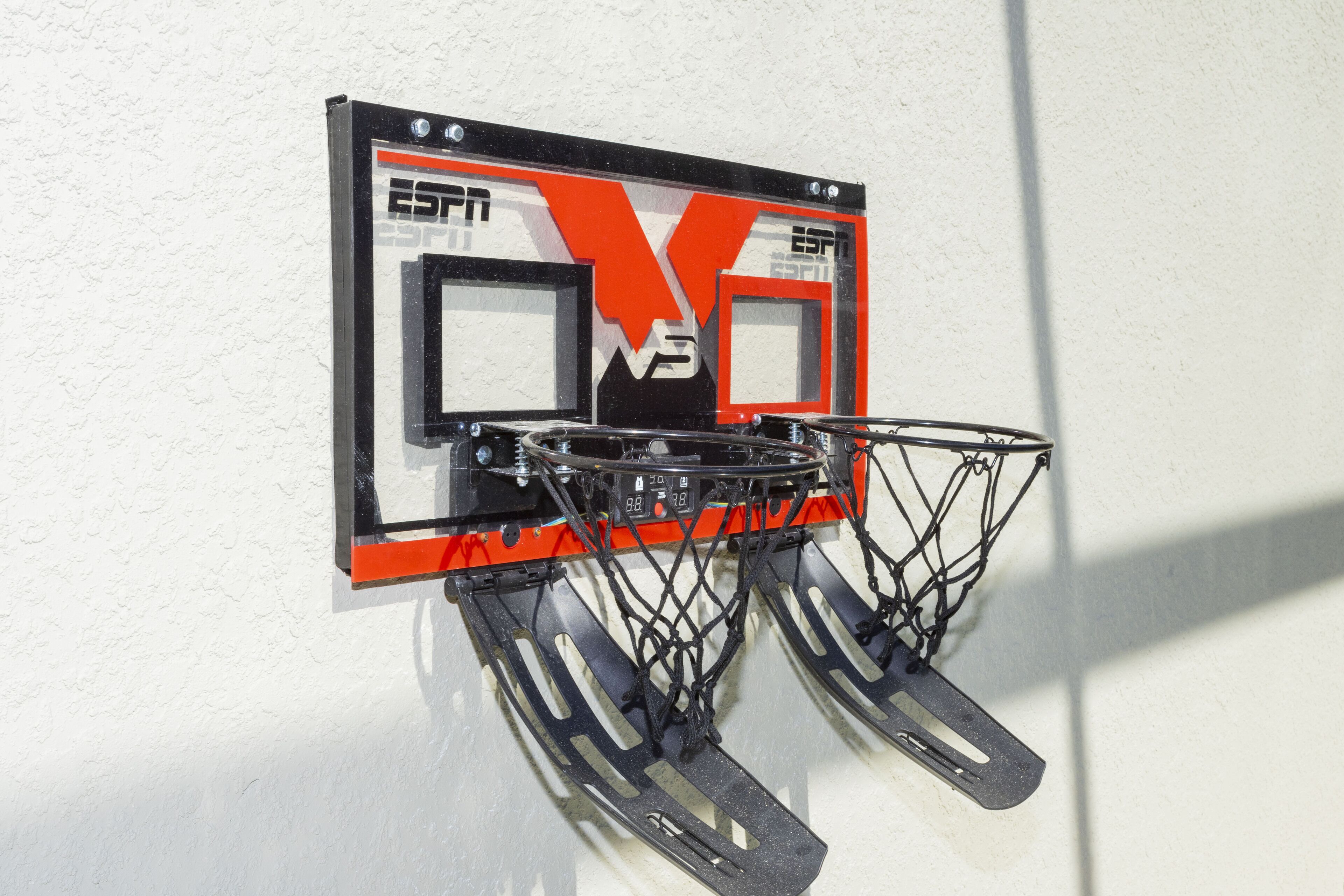 A basketball hoop mounted on a wall with a visible scoreboard and a metal frame.