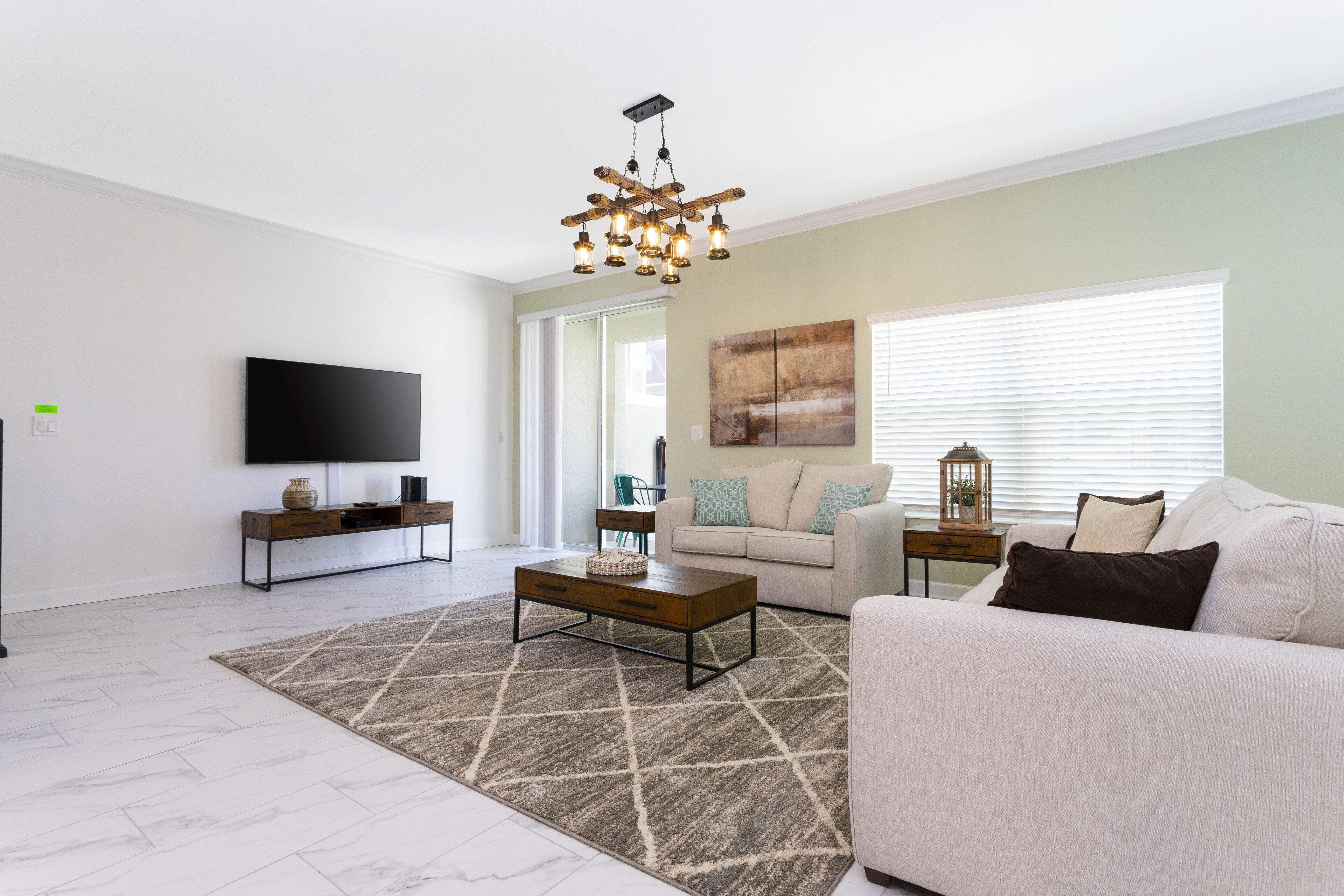 A modern living room with a flat-screen TV, a wooden coffee table, a beige sofa, and a patterned rug.