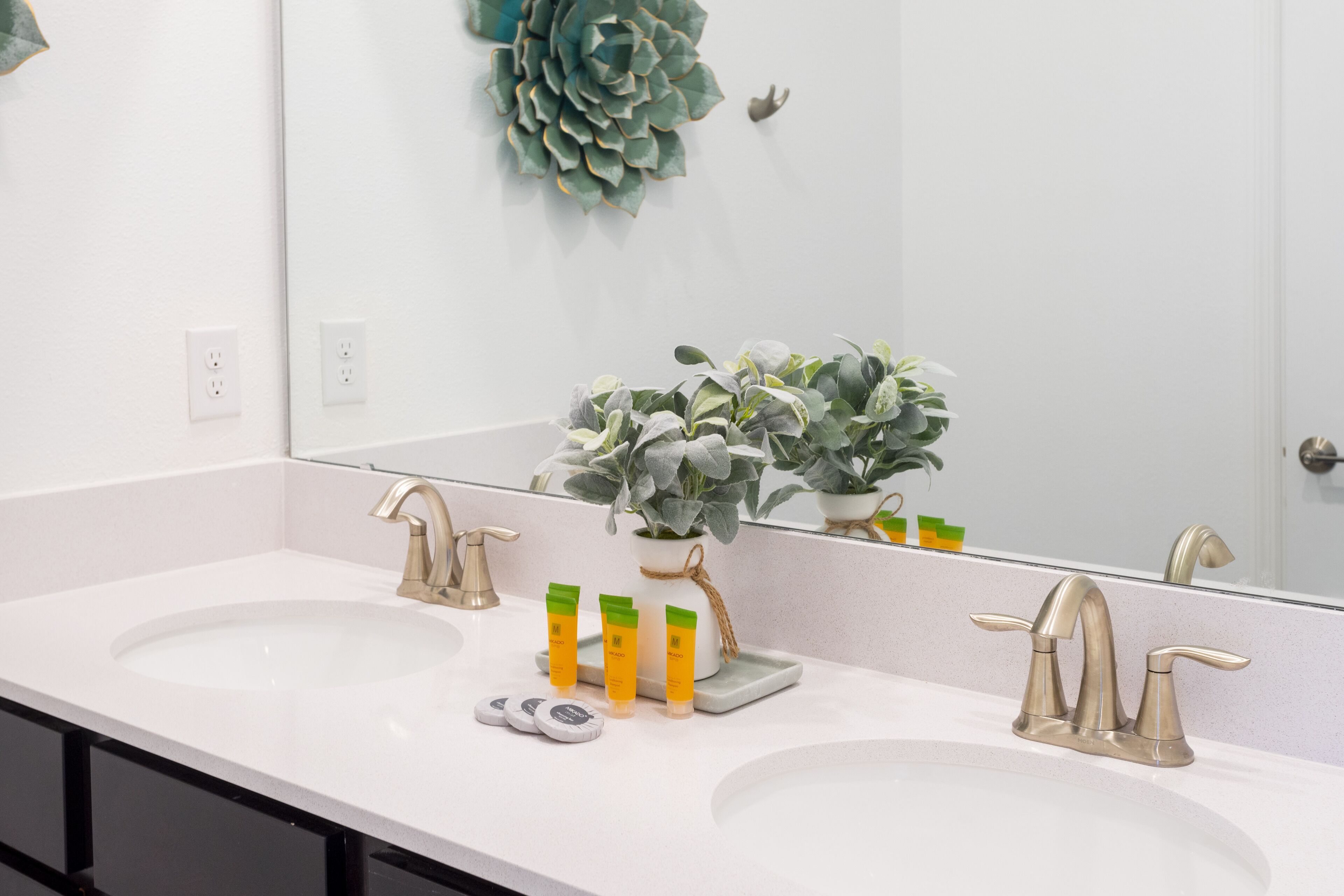 Un bagno con due lavandini, uno specchio grande e una pianta in vaso.