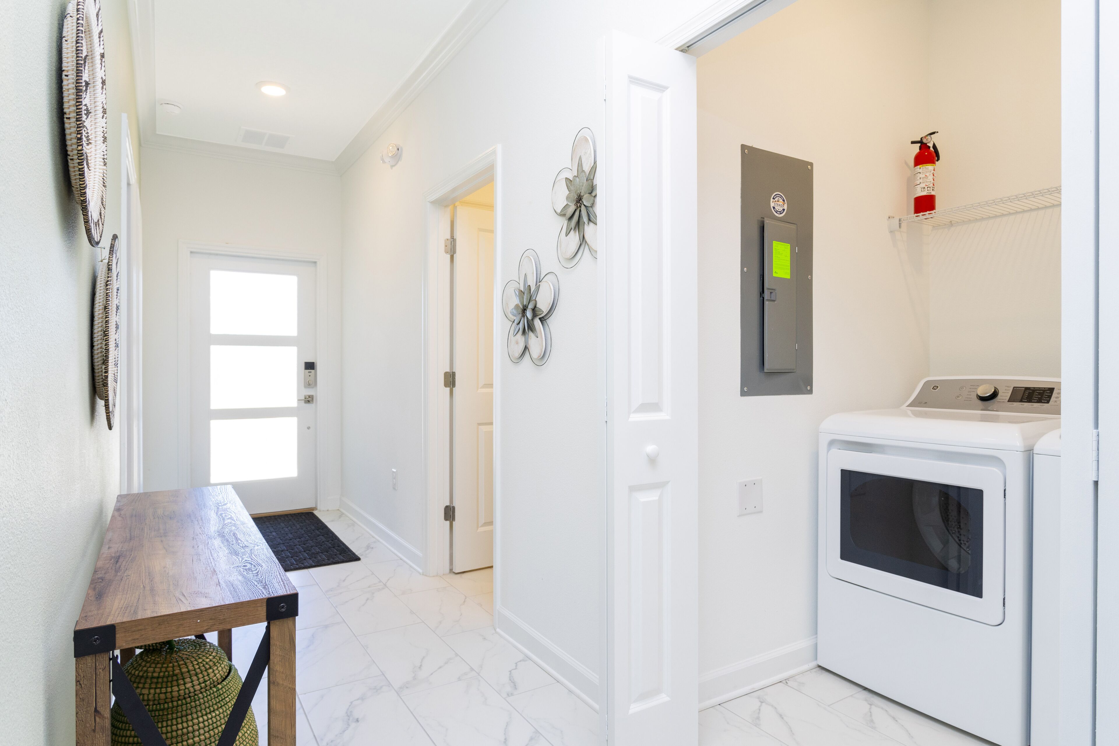 A laundry room with a washing machine, dryer, and a fire extinguisher on the wall.