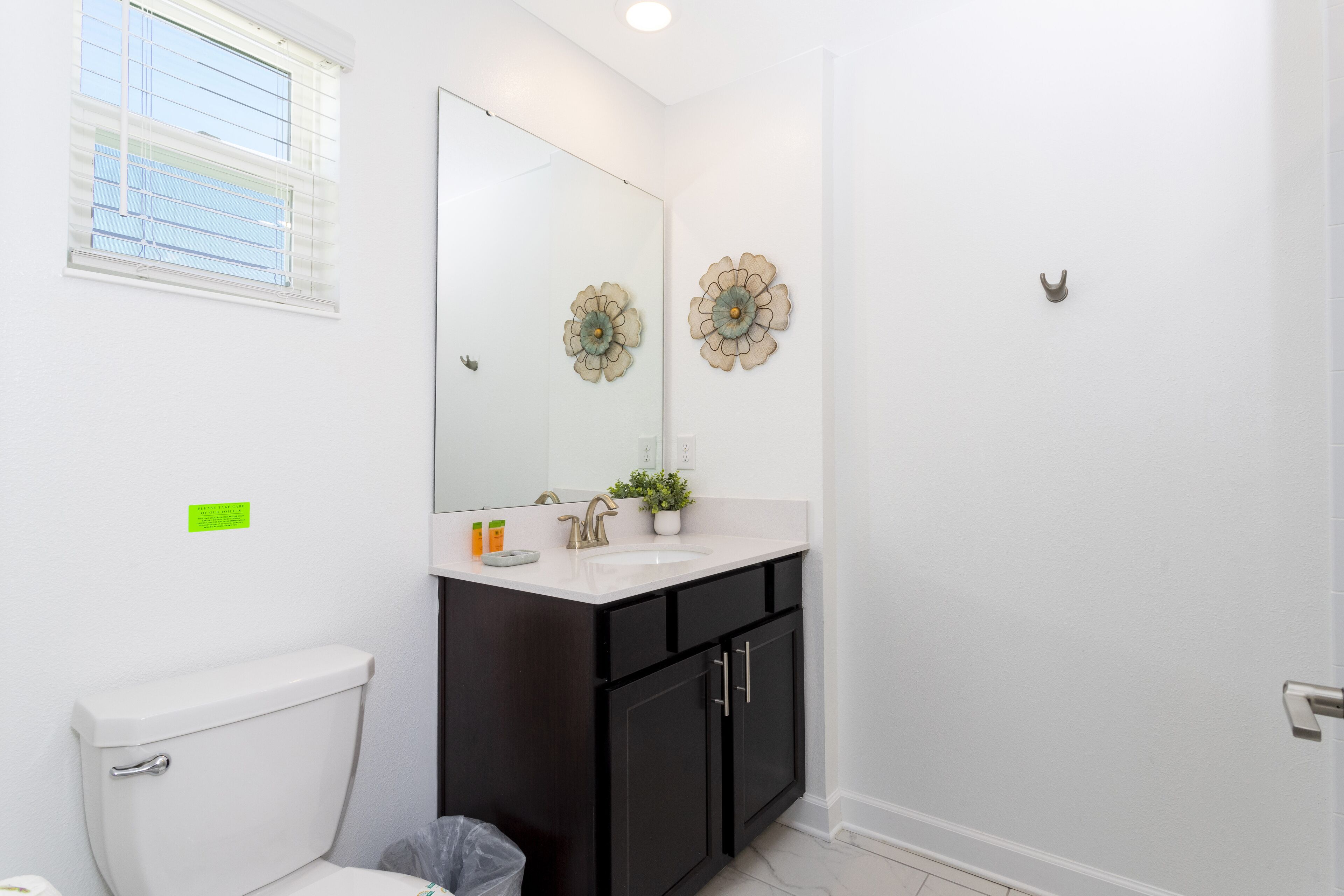 A bathroom with a white toilet, a dark wooden vanity with a sink, and decorative wall art.