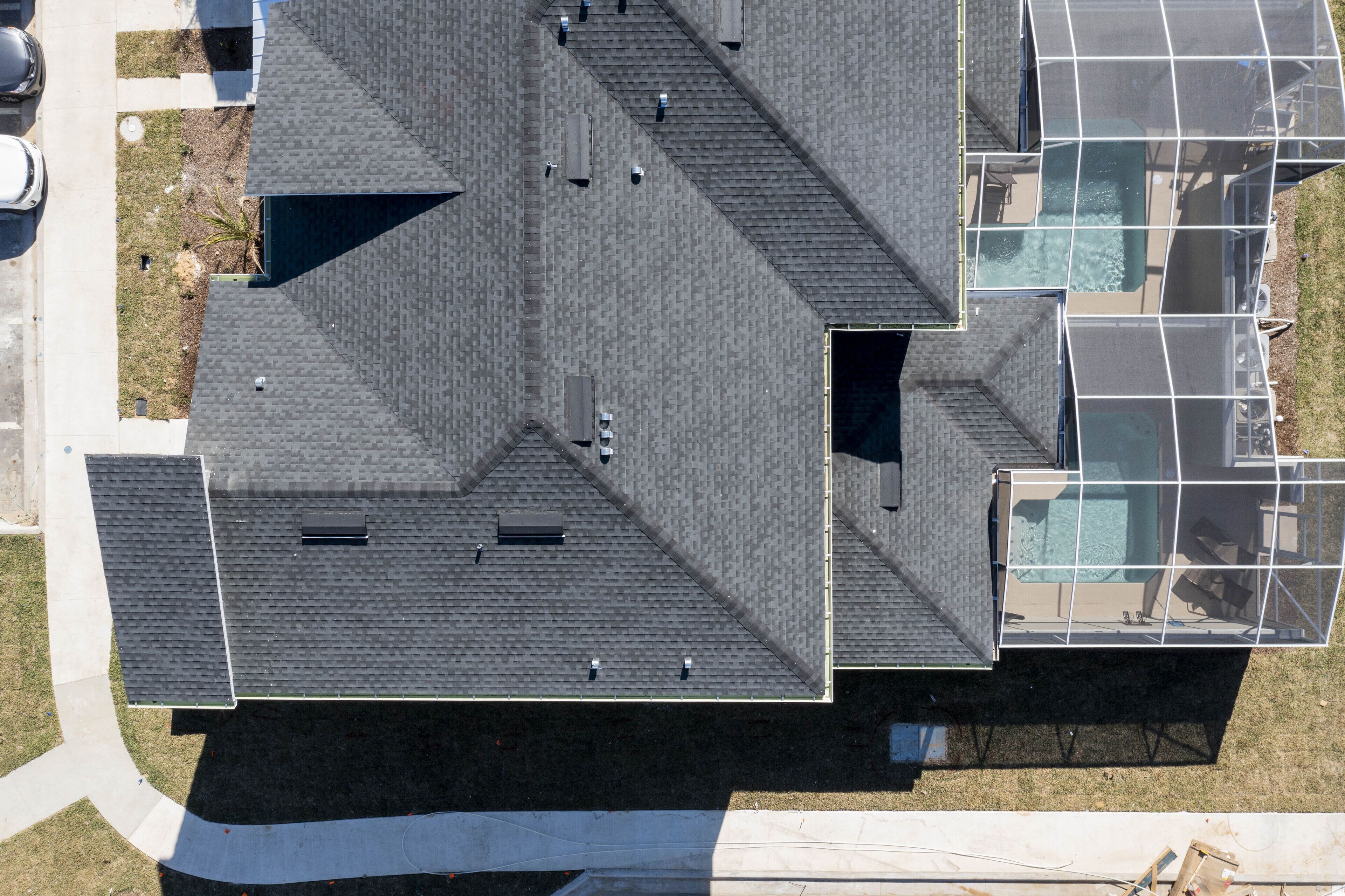 Vue aérienne d’un bâtiment doté d’un toit en pente, de plusieurs lucarnes et d’un espace piscine.