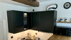 Cocina moderna con armarios negros, un lavamanos de acero inoxidable, un microondas y una encimera de madera.