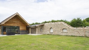 A wooden cabin with a stone wall and a grassy yard. - Owl Lodge (Wedmore)