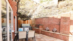 A patio with a table and chairs, a hot tub, and a brick wall. - Nant House (Wrexham)