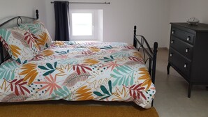 Un dormitorio con cama, cómoda y ventana con cortinas.