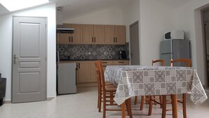 Cocina compacta con armarios de madera, salpicadero de azulejos y comedor con mesa dispuesta para cuatro personas.