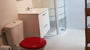 Un baño con inodoro, lavamanos y cabina de ducha.