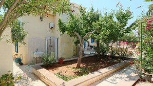 A courtyard with a tree, a small garden bed, and a tiled patio. - Villa della Libertà 10 Meters from the Sea, 10/12 SEATS, TORRE SUDA, Gallipoli (Torre Suda)