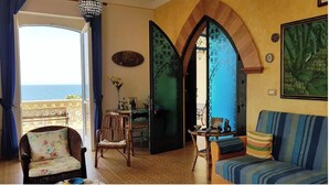 A room with a view of the sea, a wicker chair, a striped sofa, and a table with a vase of flowers. - Villa della Libertà 10 Meters from the Sea, 10/12 SEATS, TORRE SUDA, Gallipoli (Torre Suda)
