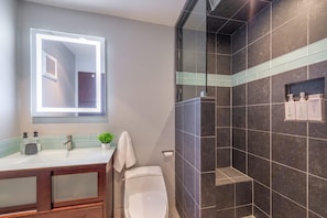Ein modernes Badezimmer mit Waschtisch, Spiegel und Dusche.