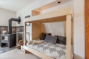 Una habitación acogedora con una litera, una chimenea y un techo de madera rústica.