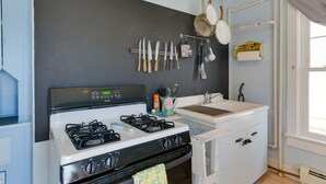 A kitchen with a gas stove, white cabinets, and a black backsplash. - 1 Block to Convention Center! Dog-Friendly Apt (Wildwood)