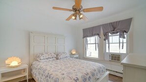 A bedroom with a bed, a nightstand, a ceiling fan, a window with curtains, and an air conditioning unit. - 1 Block to Convention Center! Dog-Friendly Apt (Wildwood)