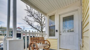 A porch with a wooden bench, a white door with a glass panel, and a white picket fence. - Near Convention Center & Boardwalk! Apt w/ Sunroom (Wildwood)