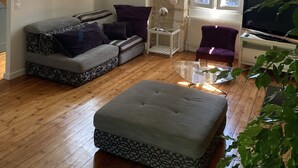 A modern living room with a sofa, ottoman, and a TV. - Charming town house with pool and garden (Périgueux)