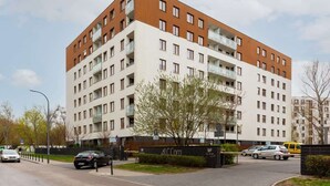 Un edificio residencial de varios pisos con balcones, un estacionamiento y un cartel de ALC Corp.