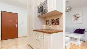 Una cocina compacta equipada con microondas, cafetera y salpicadero de azulejos.