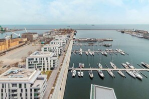 Un port de plaisance doté de plusieurs quais et abritant de nombreux bateaux, situé à côté d’un complexe immobilier moderne comprenant plusieurs étages et des balcons.